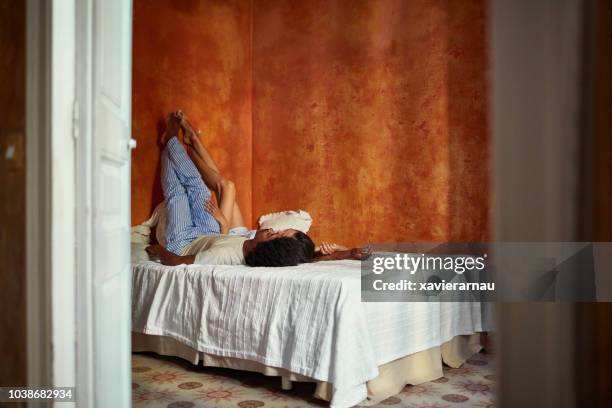 couple relaxing on bed with feet up against wall - feet up stock pictures, royalty-free photos & images