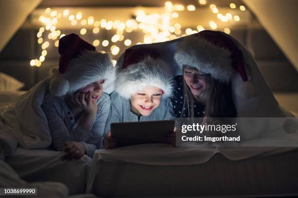 fratelli e sorelle che leggono racconti di natale su tavoletta - daily life during christmas season in poland foto e immagini stock