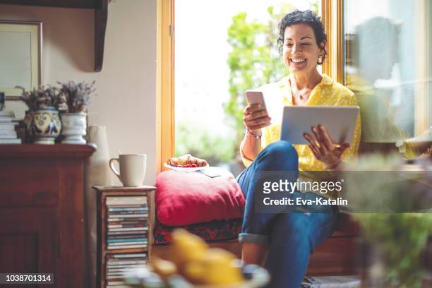 mature woman is purchasing online at home - mid adult women stock pictures, royalty-free photos & images