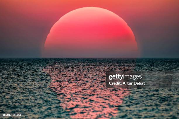 idyllic sunrise with huge sun rising over the sea. - romantischer sonnenuntergang stock-fotos und bilder