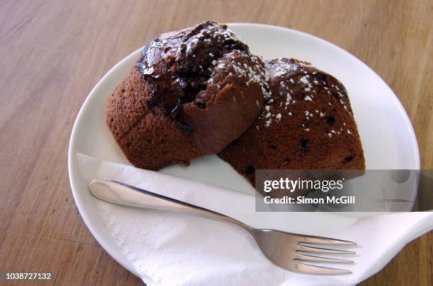 chocolate fudge muffin cut in half and served on a plate with a paper napkin and cake fork - white fudge stock pictures, royalty-free photos & images