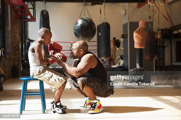 father talking to son wearing boxing gloves - kids boxing stockfoto's en -beelden