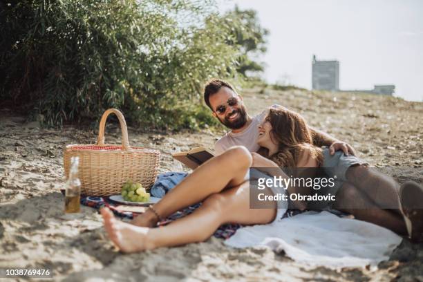 happy couple on the beach - beach book reading stock pictures, royalty-free photos & images
