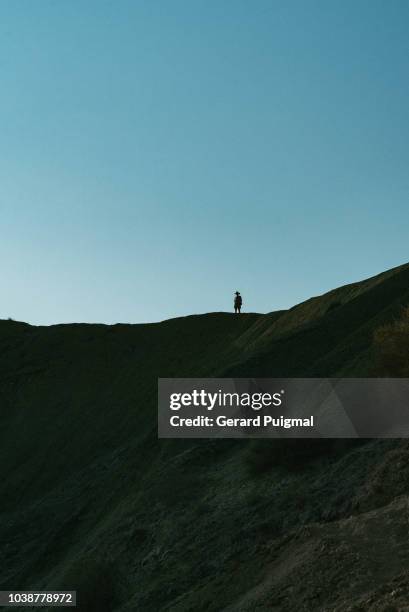 man walking on top of hills silhouetted agains the clear blue sky - malta wandern stock-fotos und bilder