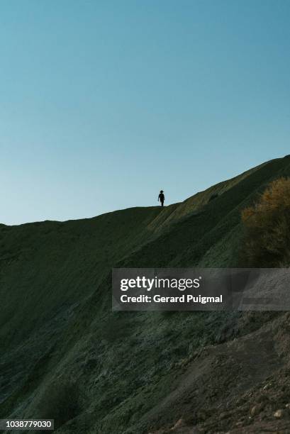 man walking on top of hills silhouetted agains the clear blue sky - malta wandern stock-fotos und bilder