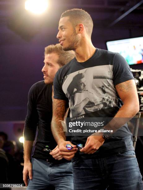 S Rafael van der Vaart and Dennis Aogo look at Aogo's throw during a show tournament with HSV players against the Professional Darts Corporation in...