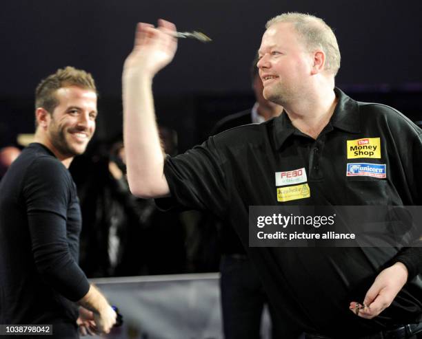 S Rafael van der Vaart watches professional dart player Raymon van Barneveld throw a dart during a show tournament with HSV players against the...