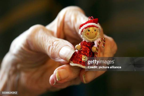 An illustrated picture shows an old lady holds a miniature of Santa Claus in her hands in the retirement home in Mainz, Germany, 19 December 2013....