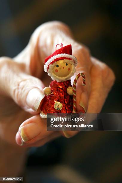 An illustrated picture shows an old lady holds a miniature of Santa Claus in her hands in the retirement home in Mainz, Germany, 19 December 2013....