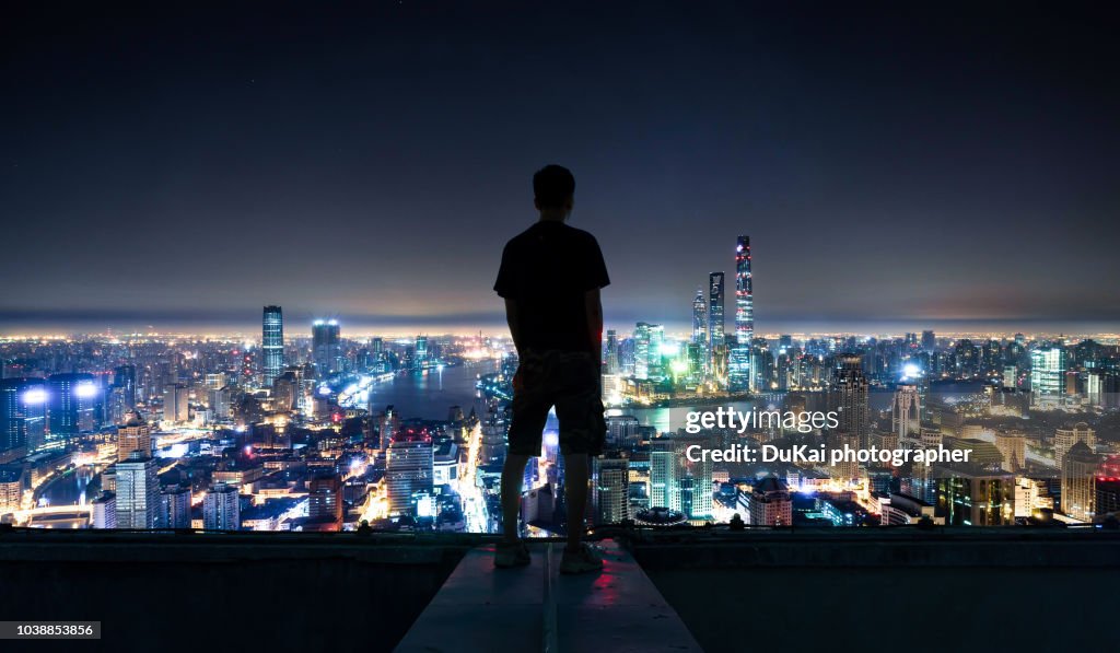 The young man stood on the roof and looked at the shanghai CBD