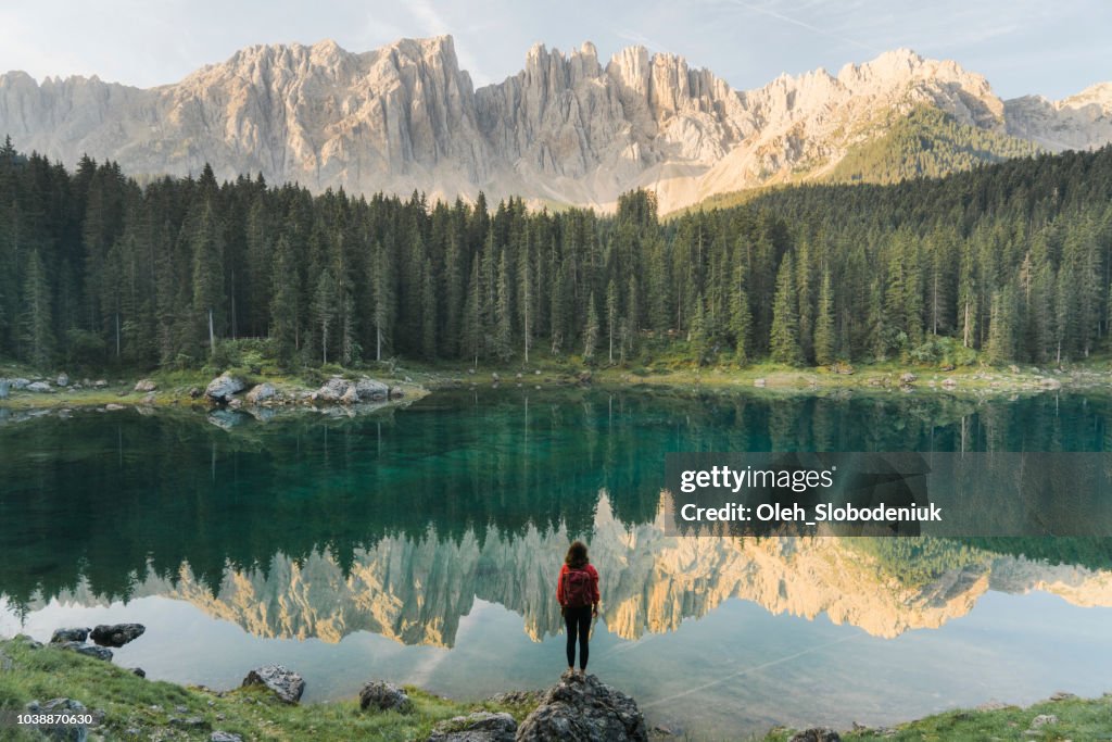 Mujer de pie y mirando el Lago di Carezza en Dolomitas