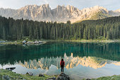 Woman standing and looking at  Lago di Carezza in Dolomites