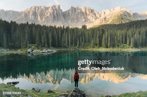 Kvinnan står och tittar på Lago di Carezza i Dolomiterna Kvinnan står och tittar på Lago di Carezza i Dolomiterna