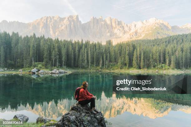 donna in piedi e guardando il lago di carezza nelle dolomiti - lago di carezza foto e immagini stock