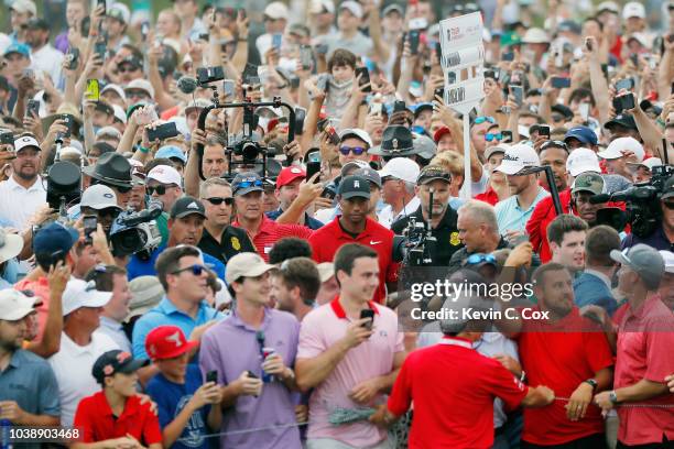 Tiger Woods of the United States is swarmed by fans as he walks to the 18th green during the final round of the TOUR Championship at East Lake Golf...