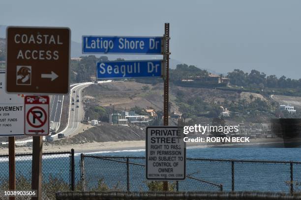 Sign indicates a Coastal Access pathway while other signs warn visitors of a private street, along the Pacific Coast Highway in Malibu, California,...