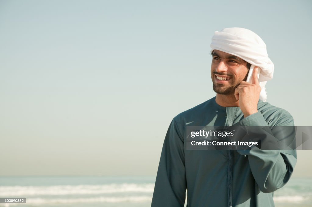 Middle Eastern man using mobile phone on the beach