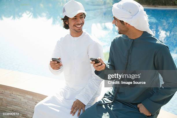 two middle eastern men with mobile phones - emirati youth stock pictures, royalty-free photos & images