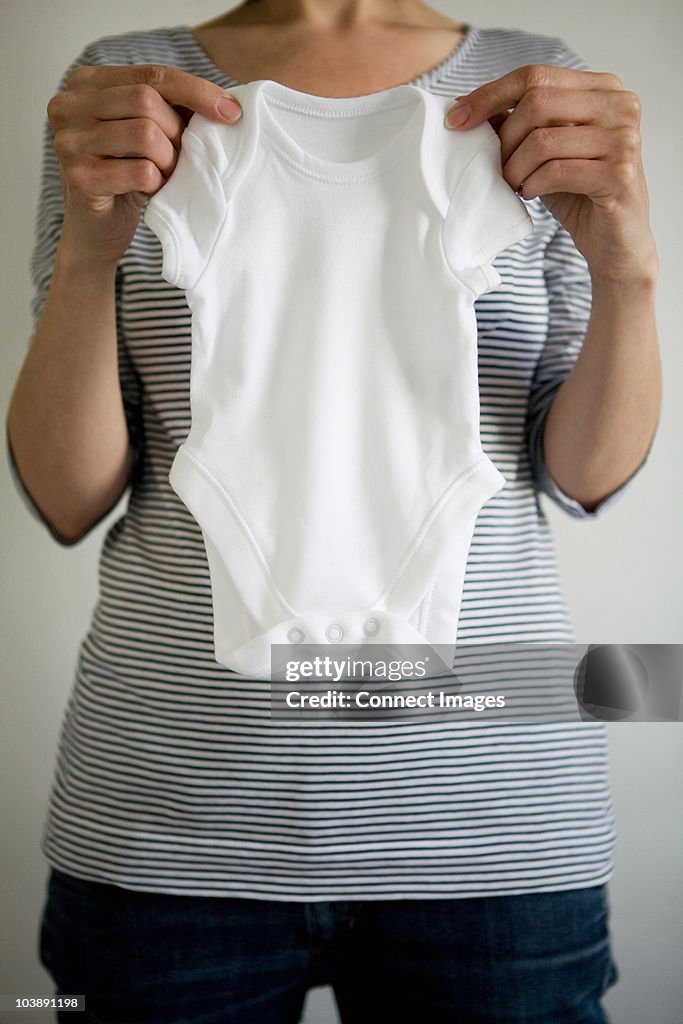 Pregnant woman holding babygro