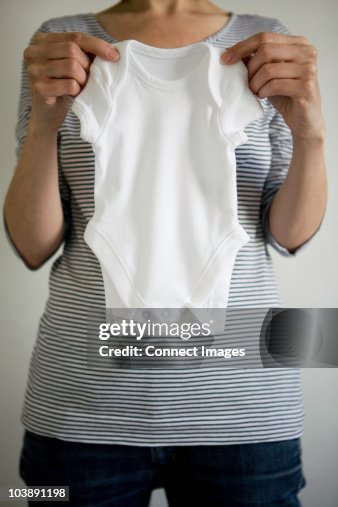 Mulher grávida segurando babygro Mulher grávida segurando babygro
