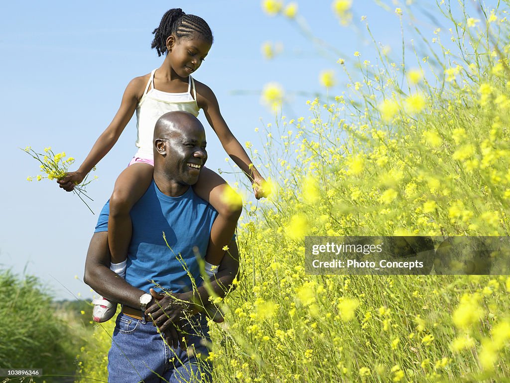 Menina e pai a correr através de um campo