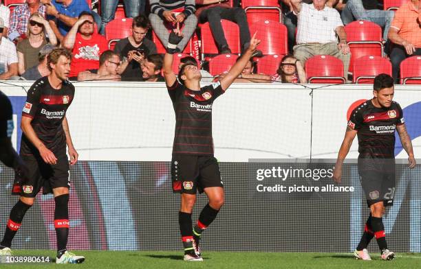 Leverkusen's Chicharito cheerss after scoring the 3:2 securing Leverkusen's victory standing next to Stefan Kießling and Charles Aranguiz in the...