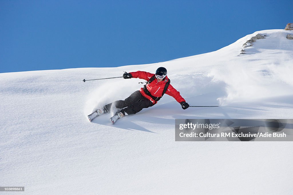 Skier carving turn through fresh powder