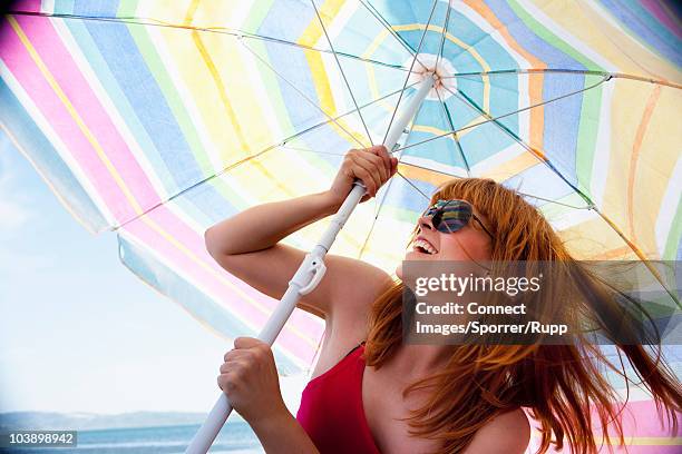 woman setting up sunshade - sonnenschutz stock-fotos und bilder