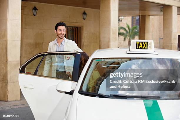 young man with open taxi door - taxi españa stockfoto's en -beelden