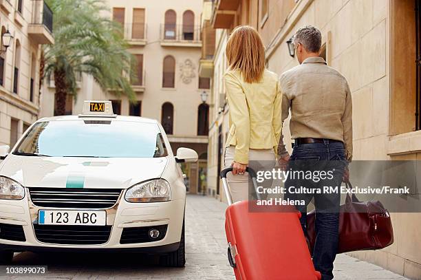 couple walking towards taxi - taxi españa stockfoto's en -beelden