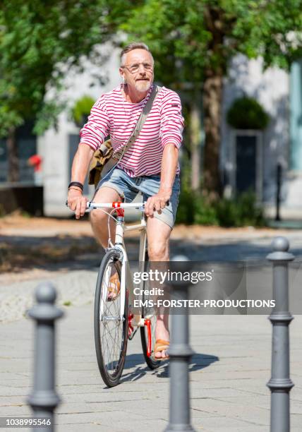 active senior man enjoys a day in the city with his stylish single speed city bike. - bike headset stockfoto's en -beelden