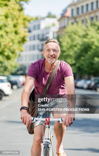 active senior man in his early 60s enjoys city life in summer. - 2018 cycling photos et images de collection