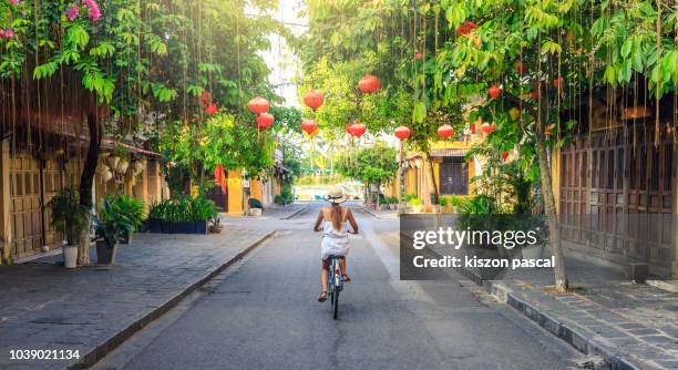 women visiting the old city of hoi an in vietnam by bike during morning - vietnamese culture 個照片及圖片檔