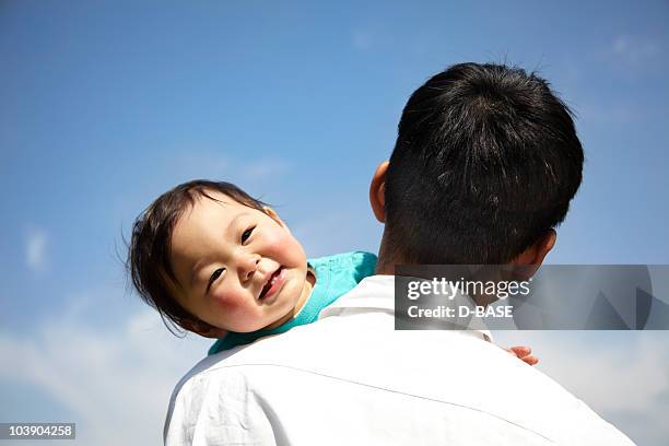 a baby boy smiling on his father's sholder. - asian smiling father son stock pictures, royalty-free photos & images