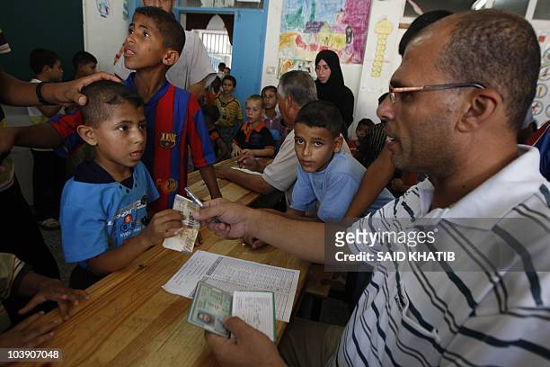 Palestinian teacher delivers bills of 100 New Israeli Shekels to primary school students in Rafah, southern Gaza Strip, on September 8, 2010. The...