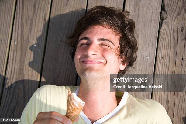 man lying on pier eating an ice cream - eating icecream stock pictures, royalty-free photos & images