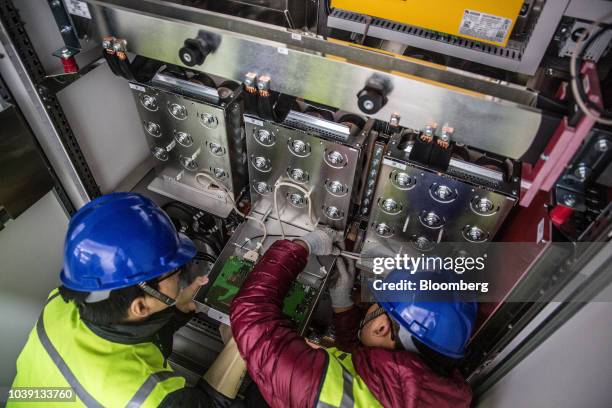 Workers replace a power inverter at the Everyday Farm LLC Monnaran Solar Farm Project, a joint venture between Bridge LLC and Farmdo Co., in...