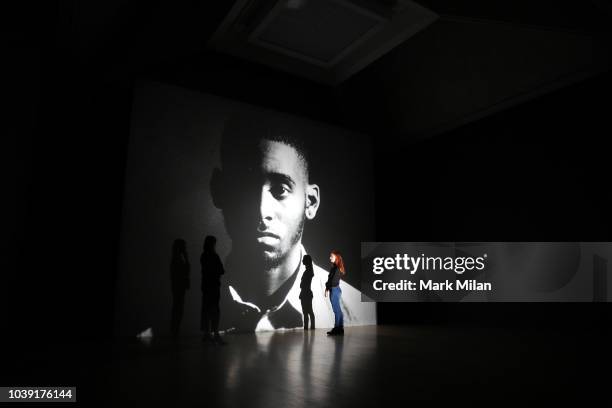 People watch a video piece by artist Luke Willis Thompson during the Turner Prize 2018 Photocall held at Tate Britian on September 24, 2018 in...