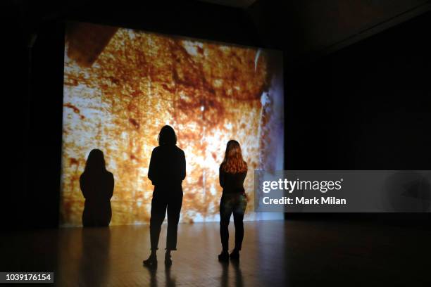 People watch a video piece by artist Luke Willis Thompson during the Turner Prize 2018 Photocall held at Tate Britian on September 24, 2018 in...