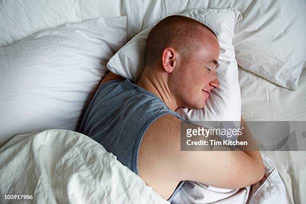 man sleeping and hugging pillow, smiling - china foto e immagini stock