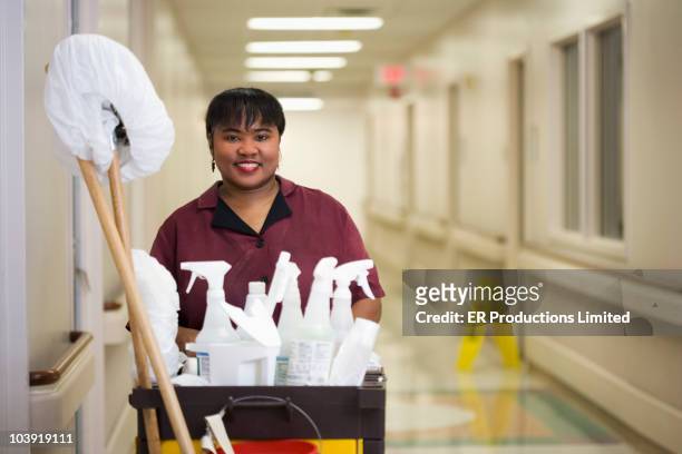 janitorial worker with cart in hospital hallway - bidello foto e immagini stock