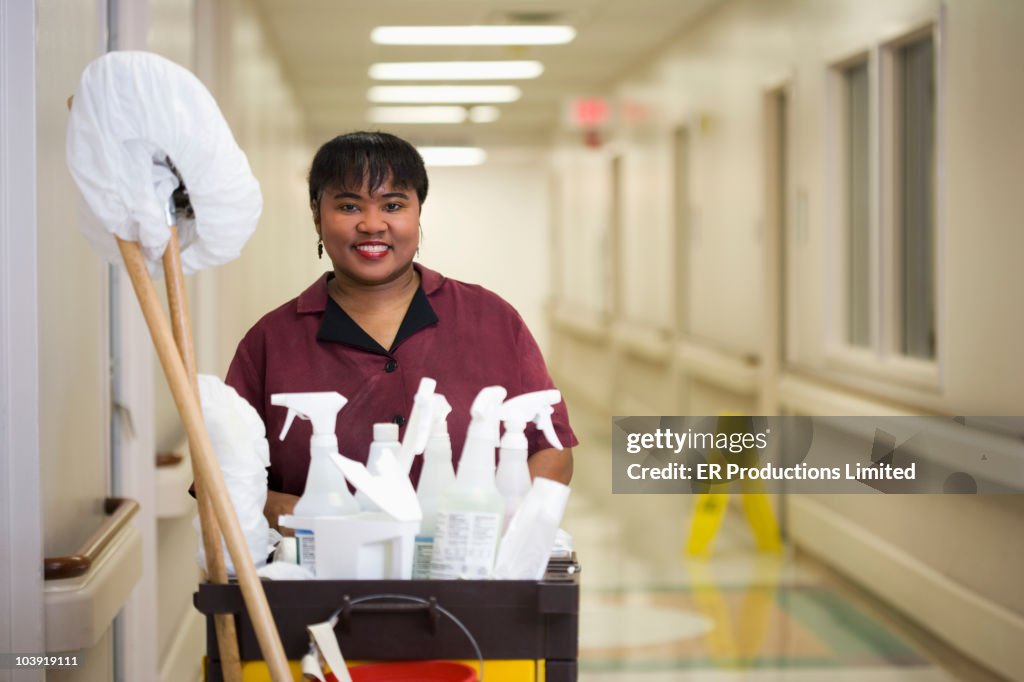 Janitorial worker with cart in hospital hallway