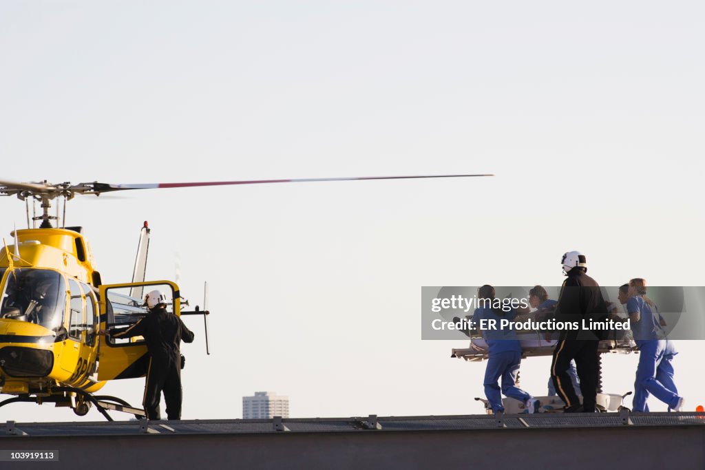 Medical personnel rushing patient to helicopter