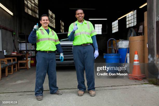 sanitation workers giving thumbs up in garage - garbage collector stock pictures, royalty-free photos & images