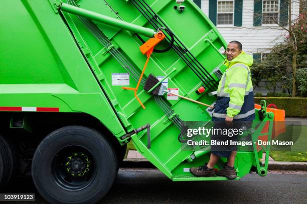 pacific islander man riding on garbage truck - müllmann stock-fotos und bilder