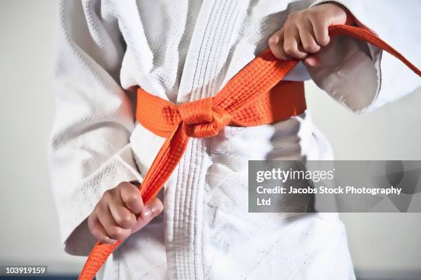 african american boy tightening karate belt - karateka stock-fotos und bilder