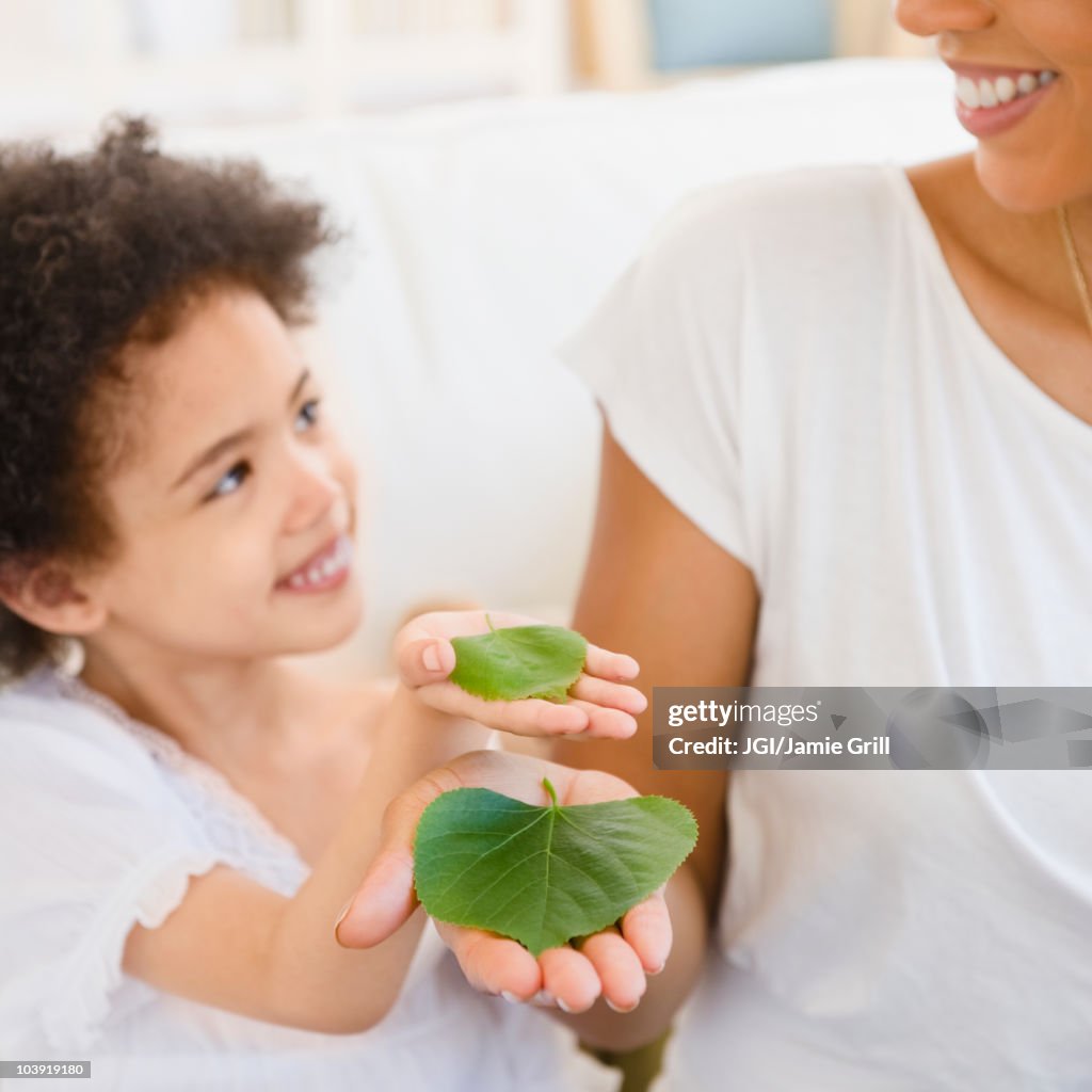 Mother and daughter holding green leaves