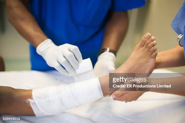 doctors treating girl's leg with bandages - fasciatura foto e immagini stock