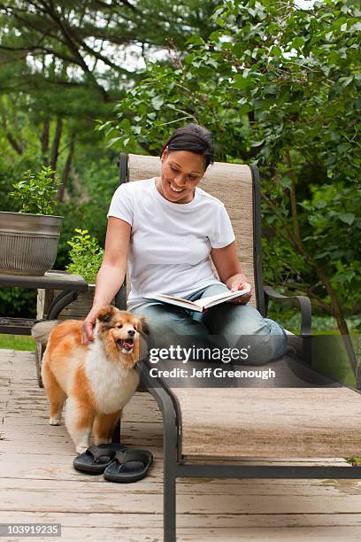 african american woman reading book and petting dog - blacksburg stock pictures, royalty-free photos & images