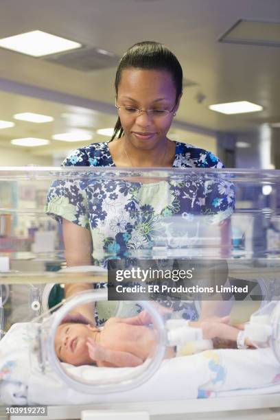 nurse examining baby in intensive care unit - black premature babies stock pictures, royalty-free photos & images